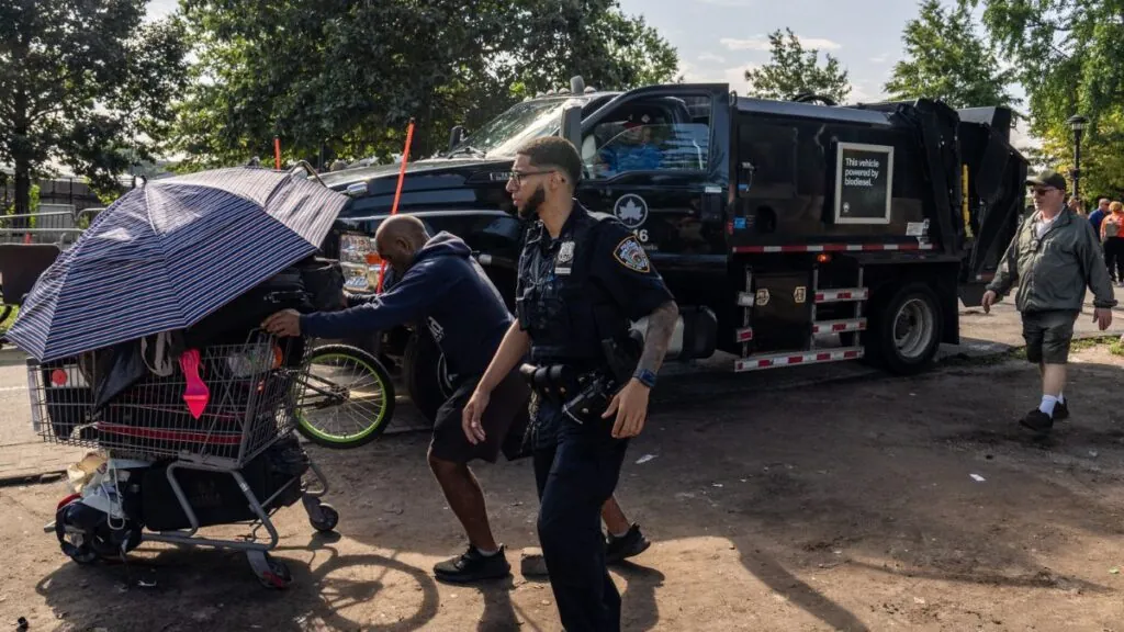 Members of the New York Police Department and Parks Department move through an encampment of homeless migrants on Randall’s Island in the Harlem River on Monday, Aug. 19, 2024